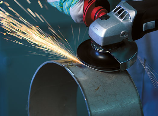 Winkelschleifer bearbeitet großes Metallrohr im Profil, dabei entstehen Funken